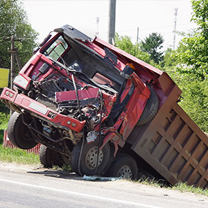 Overturned red dump truck. Expert legal help for severe trucking accident injuries.